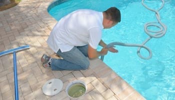 Pool expert performing maintenance on an in-ground pool